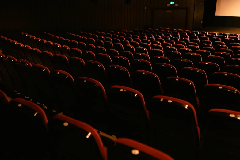 an empty theater with red seats and a projector screen, pexels, incoherents, alessio albi, imax close-up of face, ( ( theatrical ) ), contain