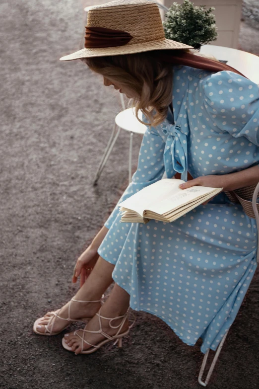 a woman sitting in a chair reading a book, by Pamela Ascherson, unsplash, blue checkerboard dress, 1 9 7 0 s style, outdoor, dots