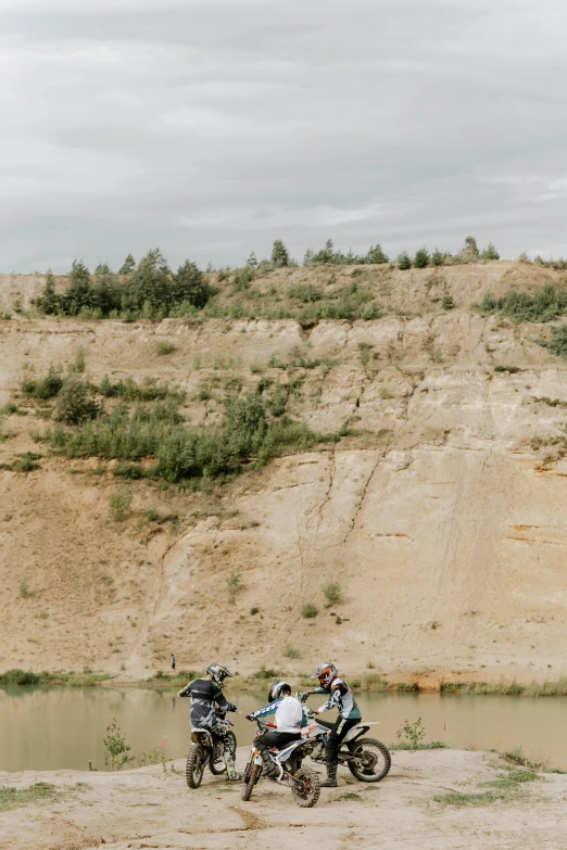 a couple of people riding on the back of motorcycles, by Grytė Pintukaitė, unsplash, romanticism, rock quarry location, panorama shot, on a riverbank, white