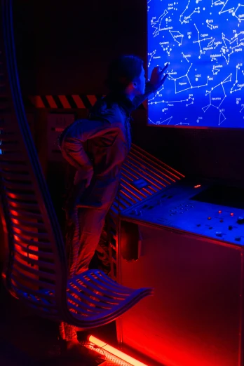 a man standing in front of a computer screen, a hologram, flickr, interactive art, detailed spaceship interior, star charts, red and blue lighting, research station