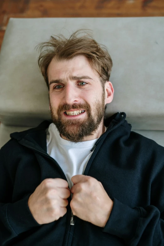 a man in a black jacket posing for a picture, in pain, smiling down from above, kacper niepokolczycki, scruffy brown beard