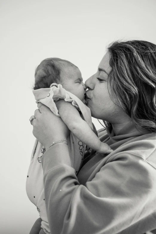 a woman holding a baby in her arms, a black and white photo, pexels contest winner, kissing each other, mirka andolfo, alanis guillen, profile image