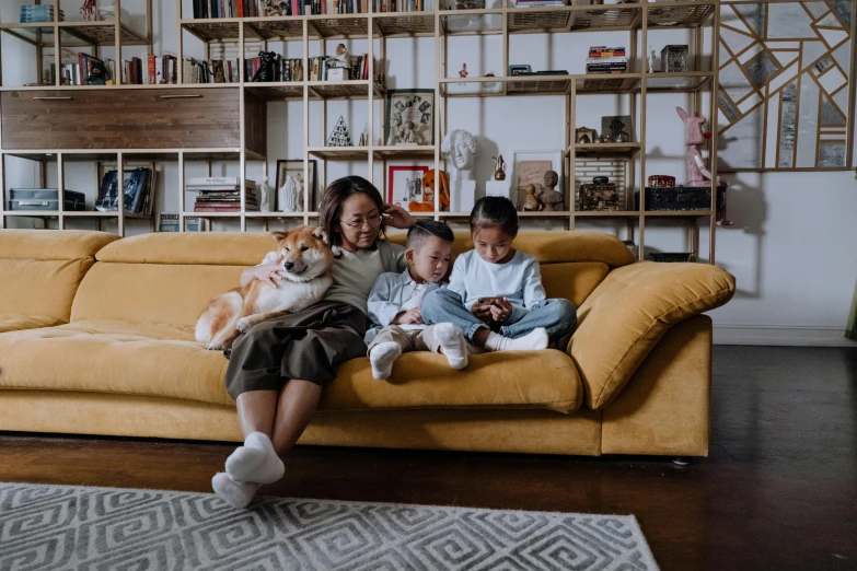 a woman sitting on a couch with two children and a dog, pexels contest winner, avatar image, asian women, popular interior design style, video footage