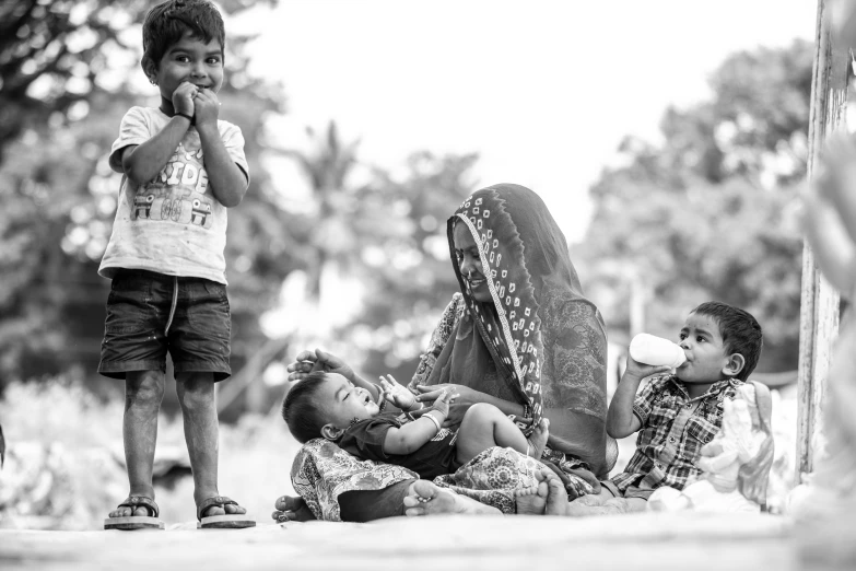 a group of children standing next to each other, a black and white photo, by Ibrahim Kodra, pexels contest winner, eating, migrant mother, on an indian street, people resting on the grass