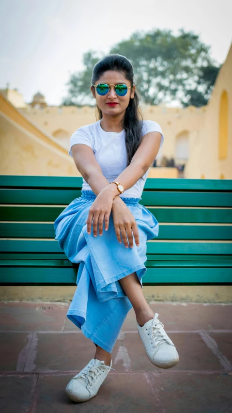 a woman sitting on top of a green bench, inspired by Bhupen Khakhar, pexels contest winner, hurufiyya, wearing blue sunglasses, dressed in a white t-shirt, 15081959 21121991 01012000 4k, portrait full body