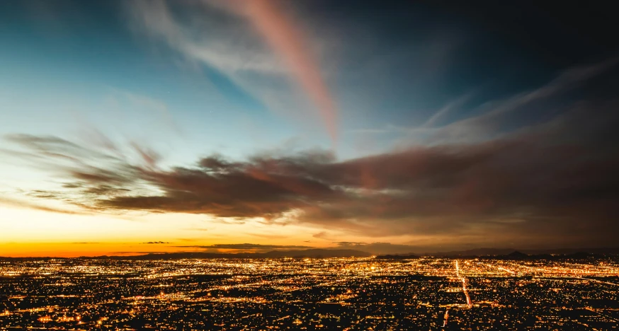 a view of a city at night with a rainbow in the sky, a tilt shift photo, unsplash contest winner, albuquerque, sunset photo at golden hour, glowing clouds, lines of lights