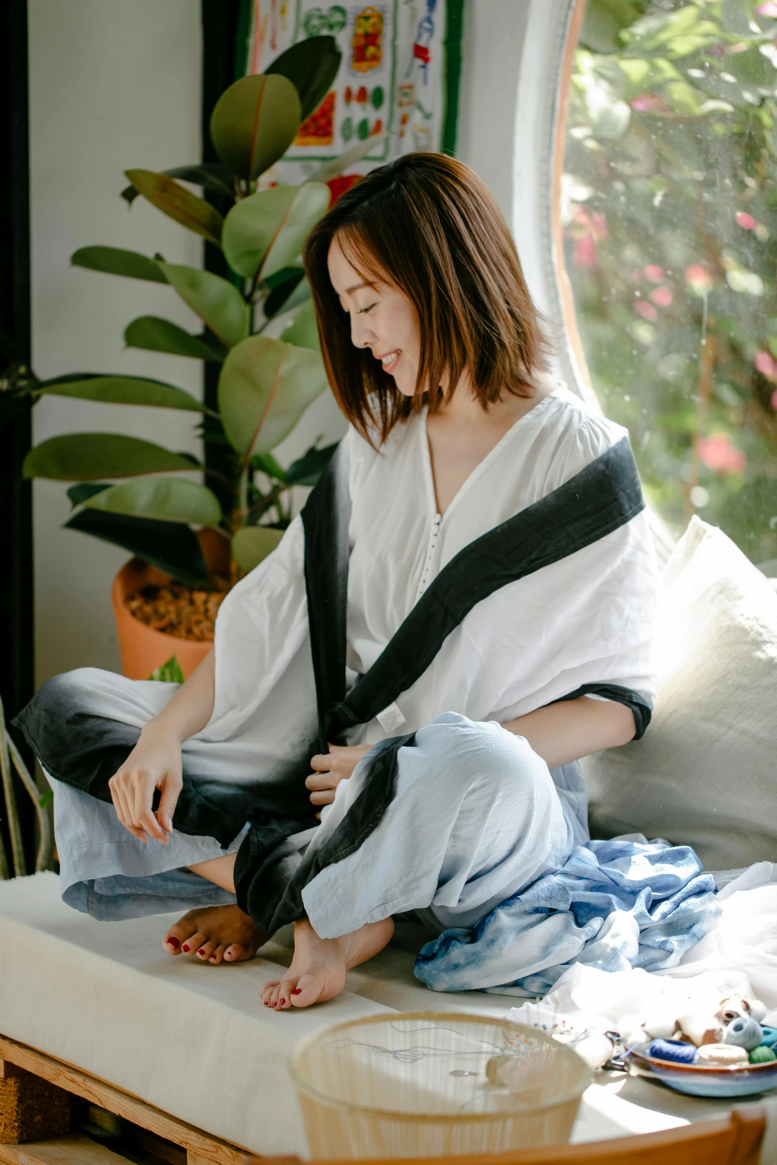 a woman sitting on a couch in a living room, inspired by Cui Bai, happening, wearing a towel, robe, pants, denim