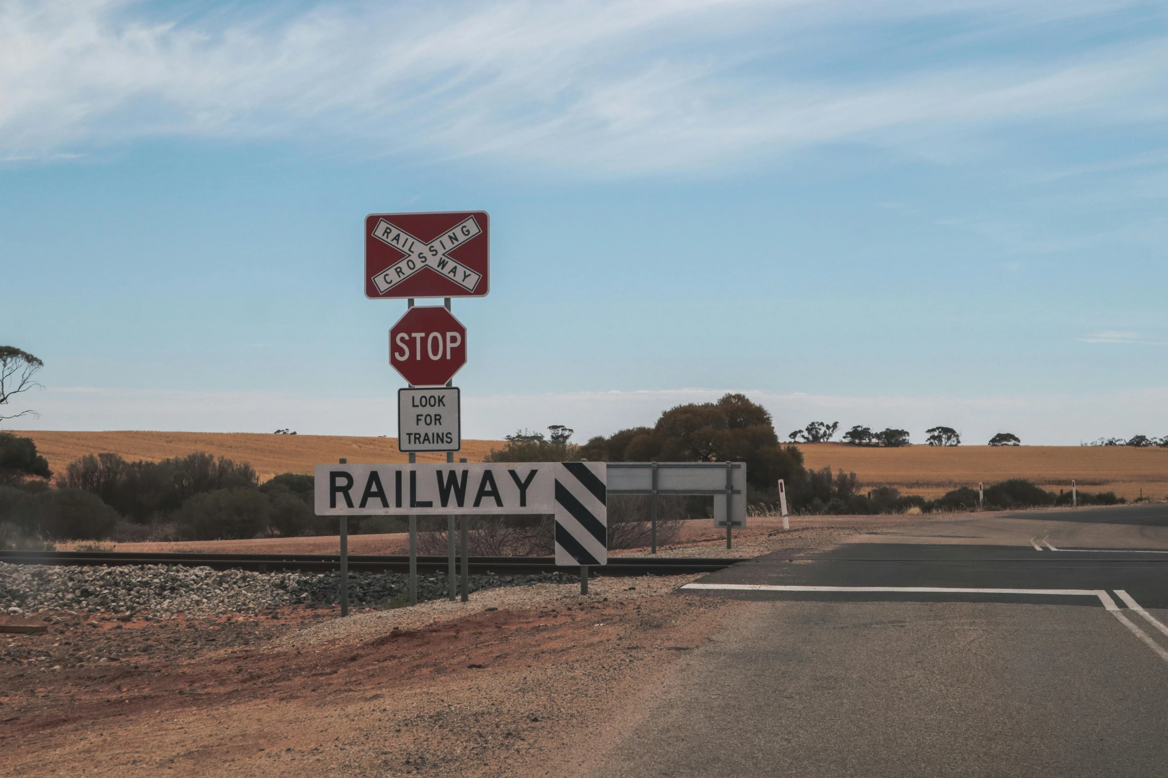 a red stop sign sitting on the side of a road, by Andrew Allan, unsplash, regionalism, rail tracks lead from the mine, southern cross, instagram post, 🚿🗝📝