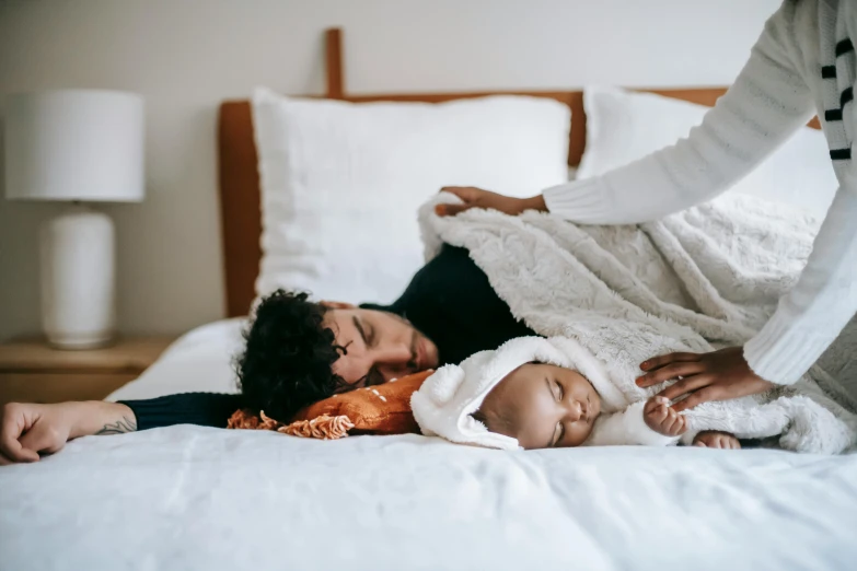 a woman laying on top of a bed next to a baby, pexels contest winner, symbolism, husband wife and son, holding each other, diverse, humans sleeping in healing pods