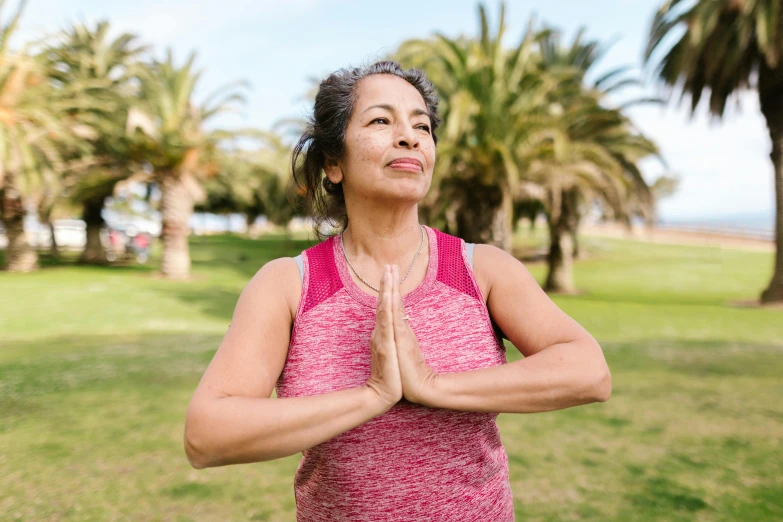 a woman doing yoga in a park with palm trees in the background, a portrait, pexels contest winner, happening, wrinkles and muscles, avatar image, half body photo, praying posture