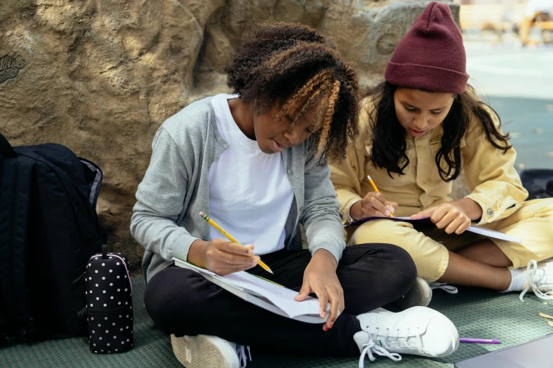 a couple of girls sitting next to each other on the ground, a child's drawing, trending on pexels, academic art, holding notebook, black teenage girl, geology, in an urban setting