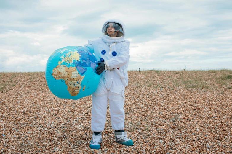 a person in a space suit holding a globe, by Alison Watt, pexels contest winner, afrofuturism, full body with costume, he is covered with barnacles, fancy dress, plain uniform sky