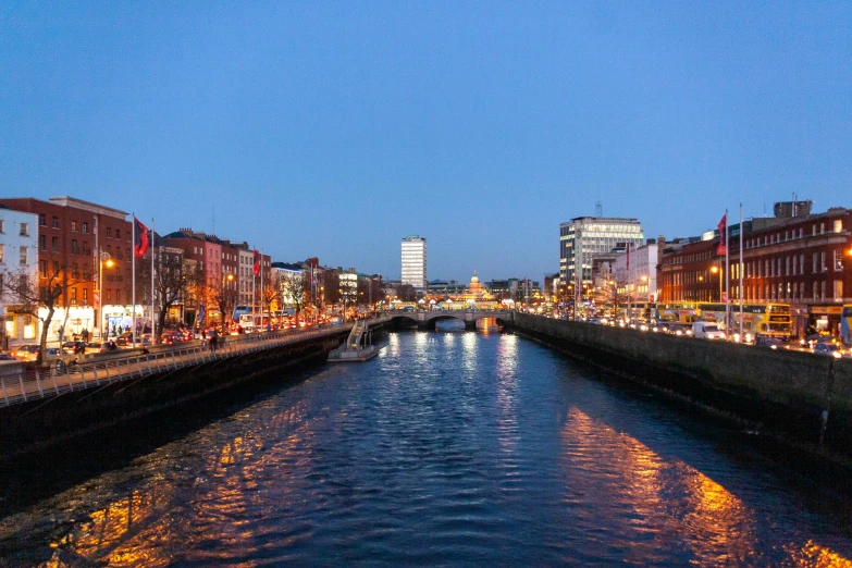 a river running through a city next to tall buildings, inspired by Mór Than, in the evening, ireland, evenly lit, canal