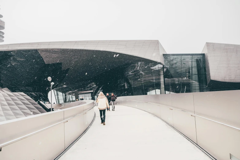 a person walking down a snow covered walkway, inspired by Zaha Hadid, unsplash contest winner, hypermodernism, bjarke ingels, exterior view, car, arena