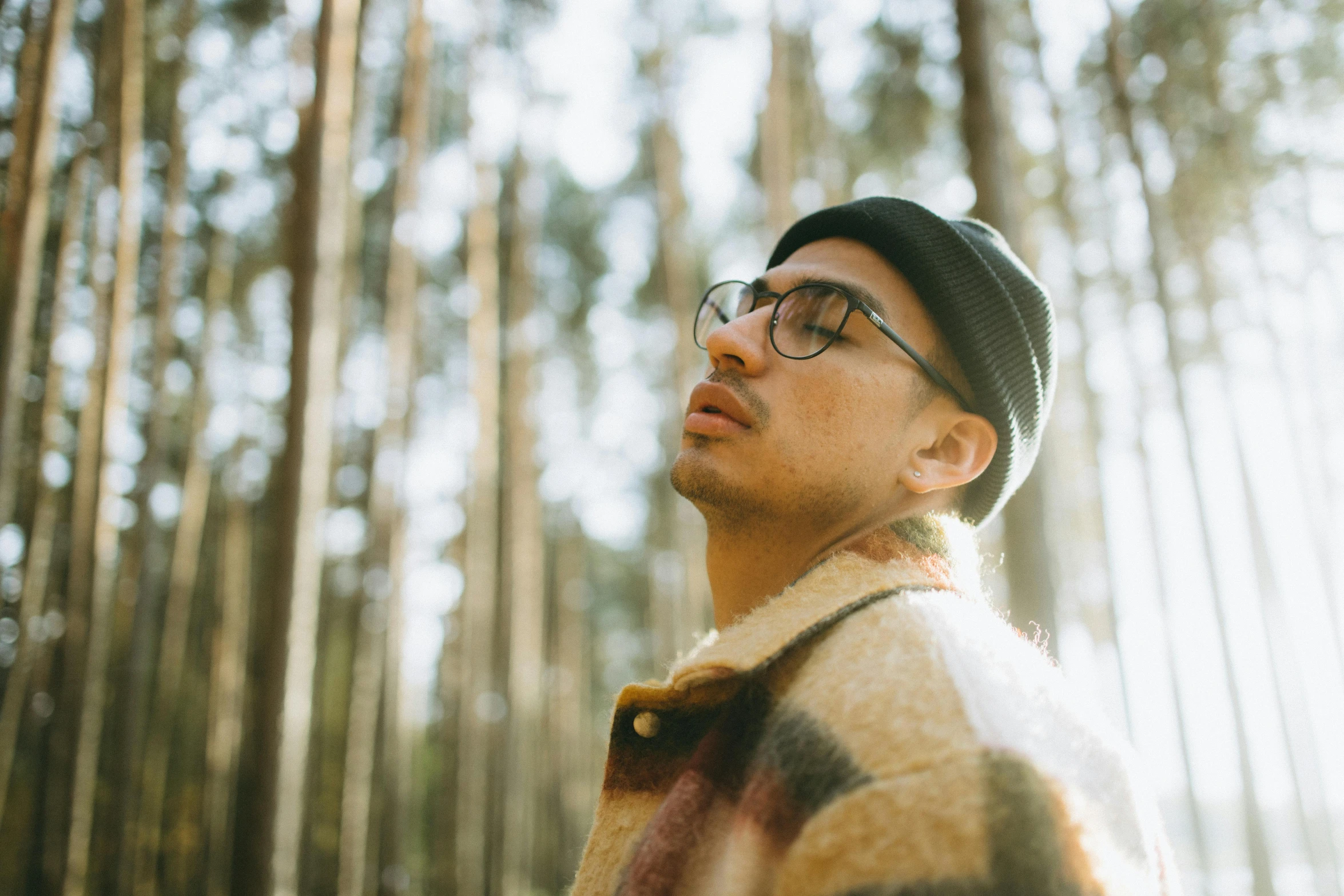 a man standing in the middle of a forest, by Emma Andijewska, trending on unsplash, in square-rimmed glasses, ashteroth, soft light.4k, lean man with light tan skin