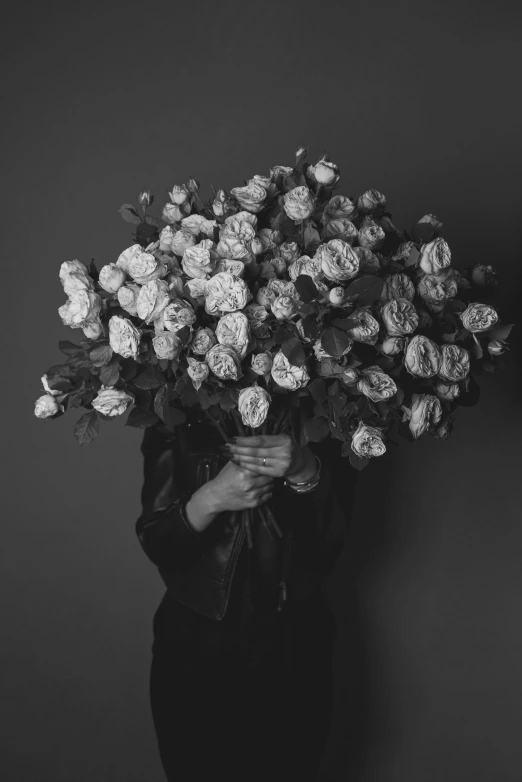 a woman holding a bunch of flowers in her hands, a black and white photo, inspired by Robert Mapplethorpe, pexels contest winner, alternate album cover, sad men, roses, covered