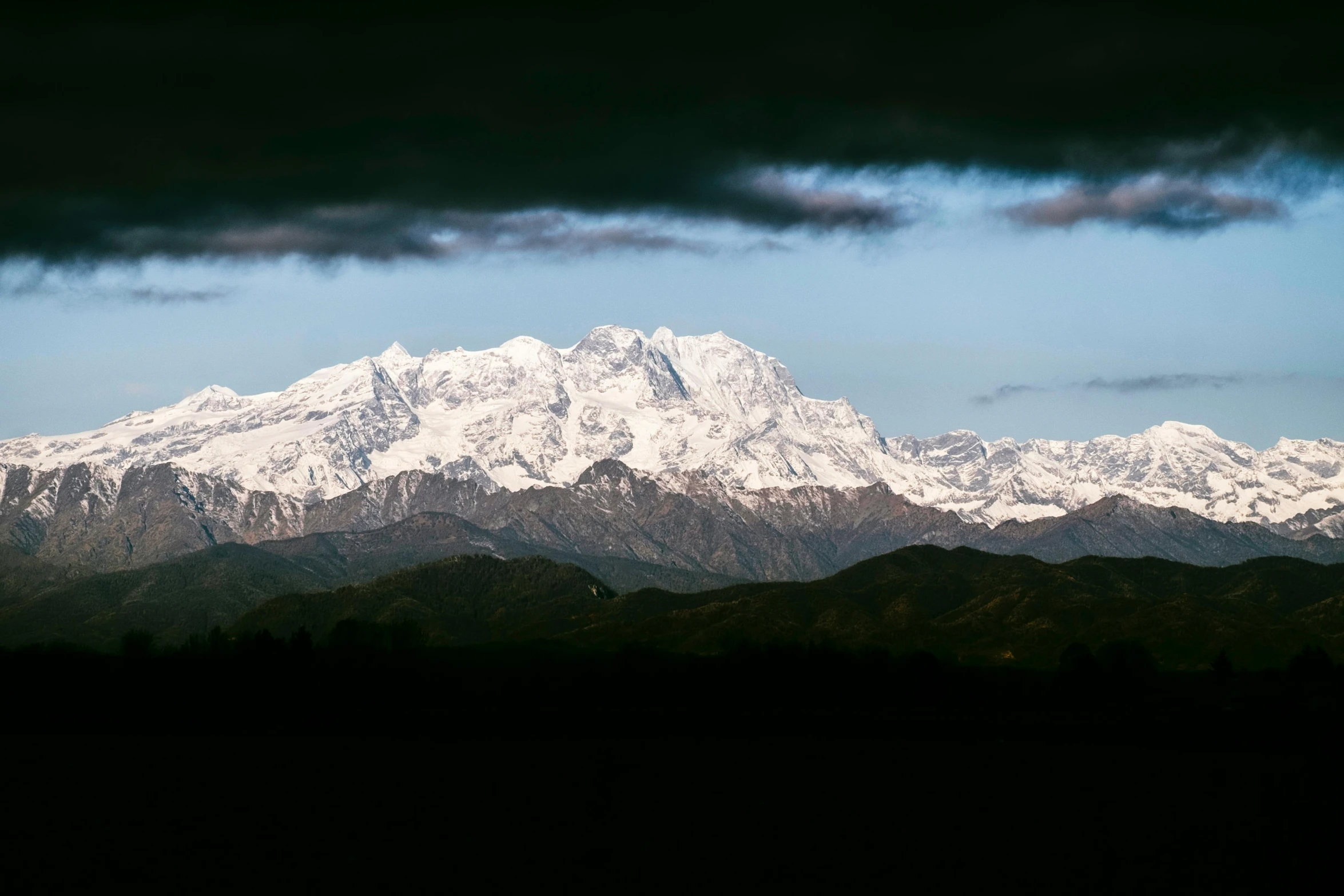 a mountain covered in snow under a cloudy sky, a portrait, unsplash contest winner, romanticism, uttarakhand, multiple stories, distant mountains lights photo