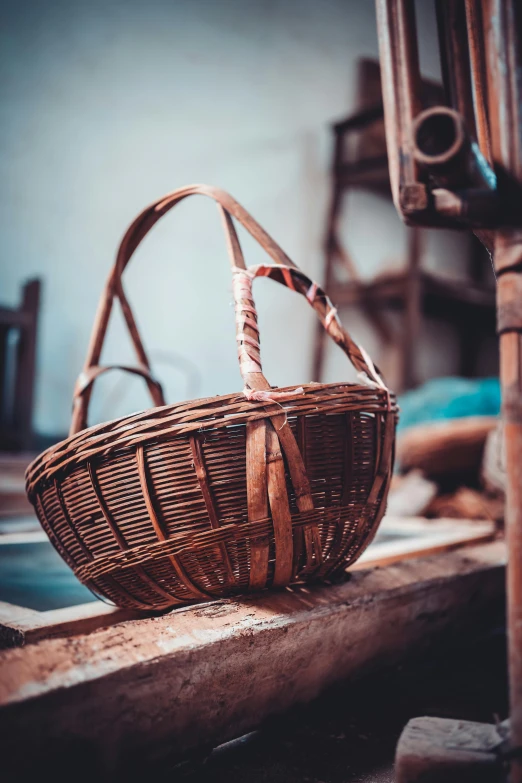 a wicker basket sitting on top of a window sill, by Thomas Furlong, pexels contest winner, arts and crafts movement, carrying a saddle bag, in a workshop, malaysian, restoration