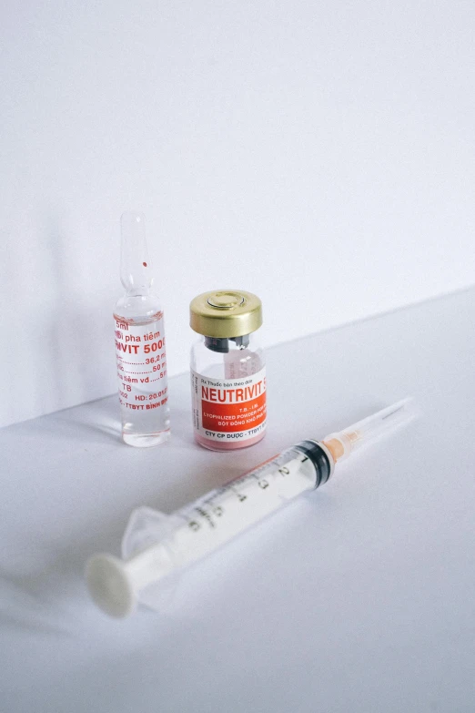 a syll sitting on top of a table next to a bottle of medicine, by Sebastian Vrancx, unsplash, syringes, set against a white background, white and orange, dermal implants