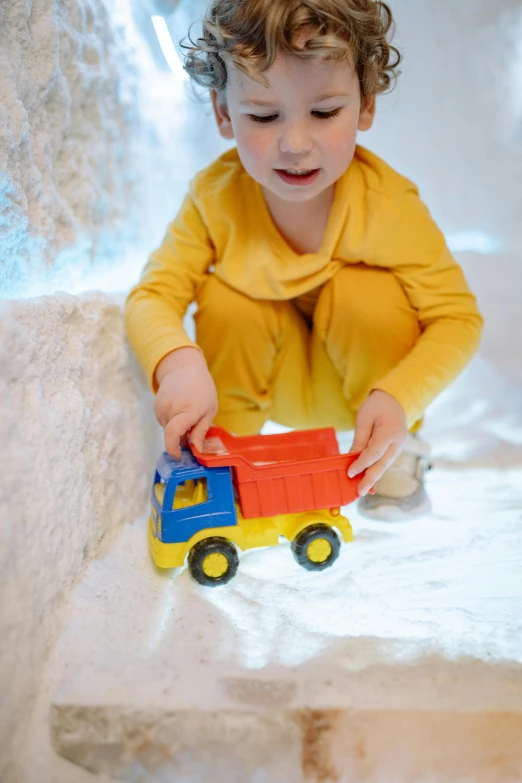 a small child playing with a toy truck, in an icy cavern, hansa yellow, soft volume absorbation, thumbnail