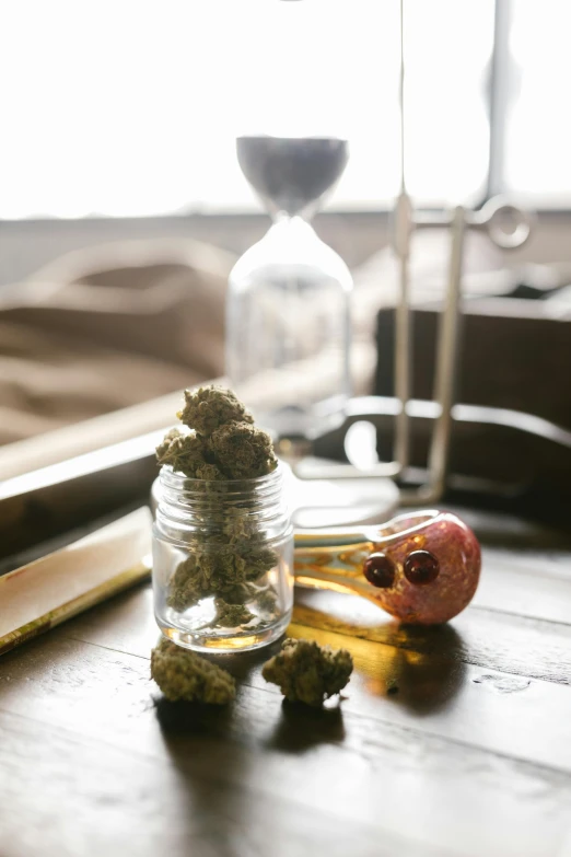 a glass jar sitting on top of a wooden table, weed, various items, day time, sitting on a lab table