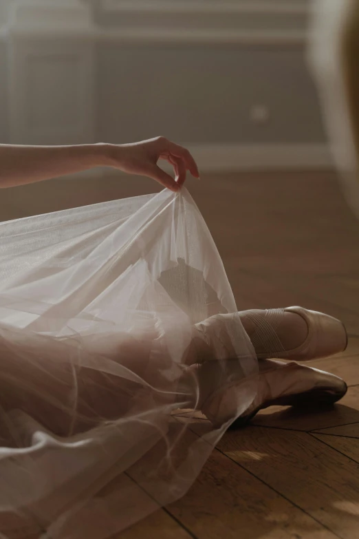 a woman in a white dress sitting on the floor, by Elizabeth Polunin, unsplash contest winner, arabesque, wearing translucent sheet, shows a leg, end of the day, wearing a pink romantic tutu