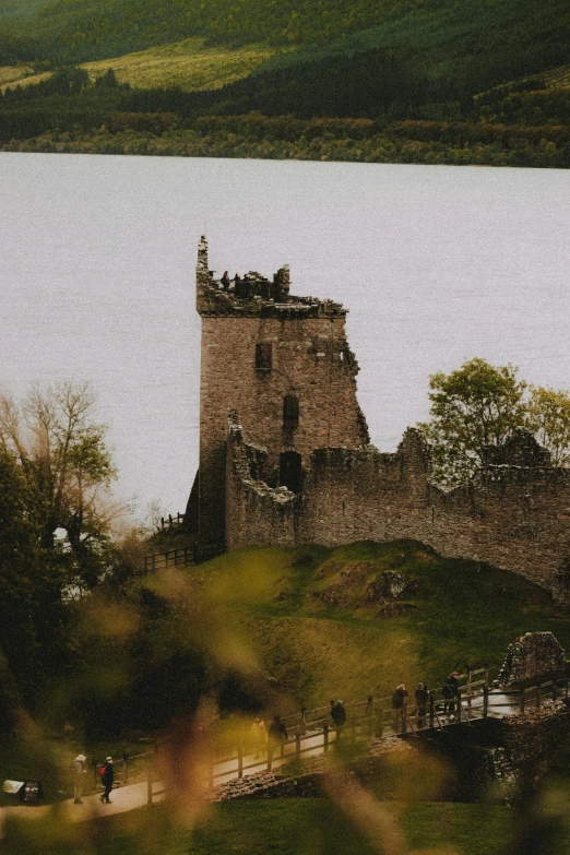 a castle sitting on top of a lush green hillside, an album cover, pexels contest winner, loch ness monster, telephoto shot, old ruins, a handsome