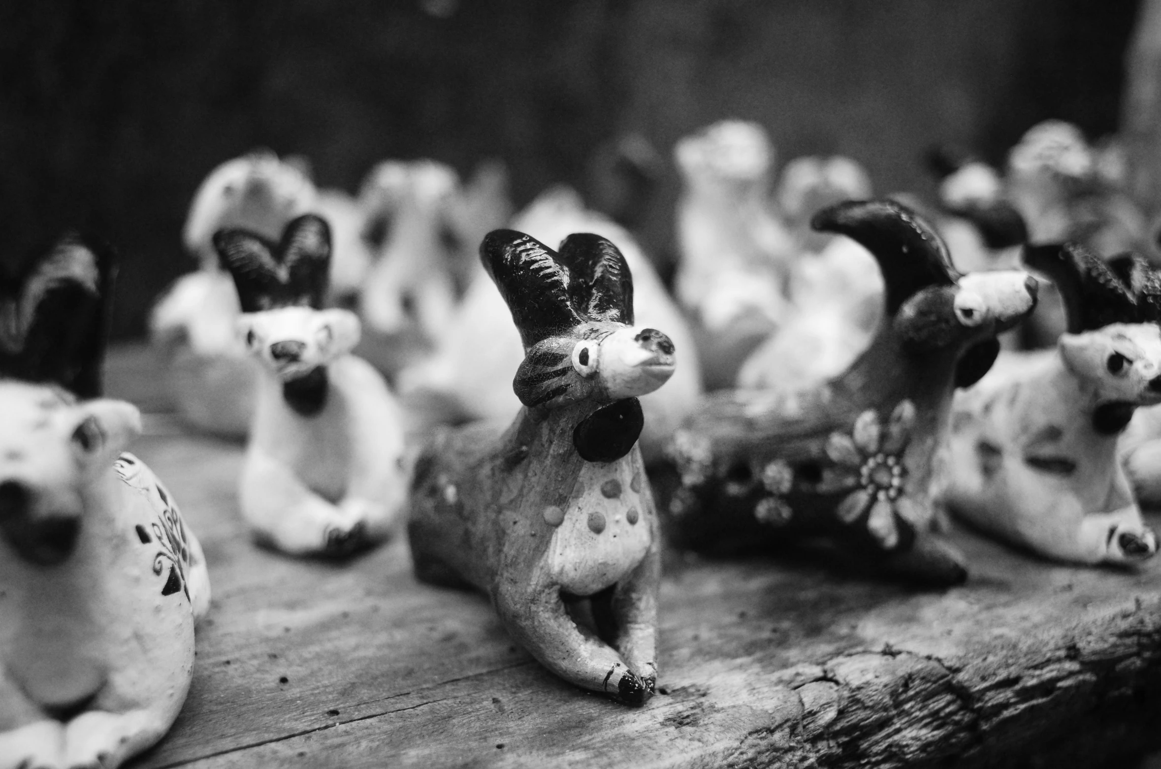 a group of animal figurines sitting on top of a wooden table, a black and white photo, by Maurycy Gottlieb, unsplash, folk art, horned ram goddess, 3 5 mm lomography, made of clay, 1952