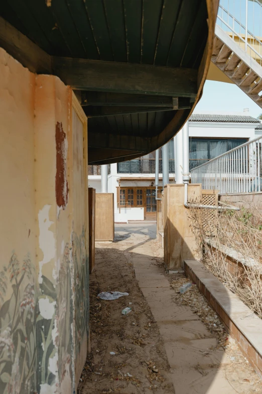 a building with graffiti on the side of it, an album cover, by Jang Seung-eop, graffiti, rammed earth courtyard, long shot from back, narrow footpath, photo from the dig site