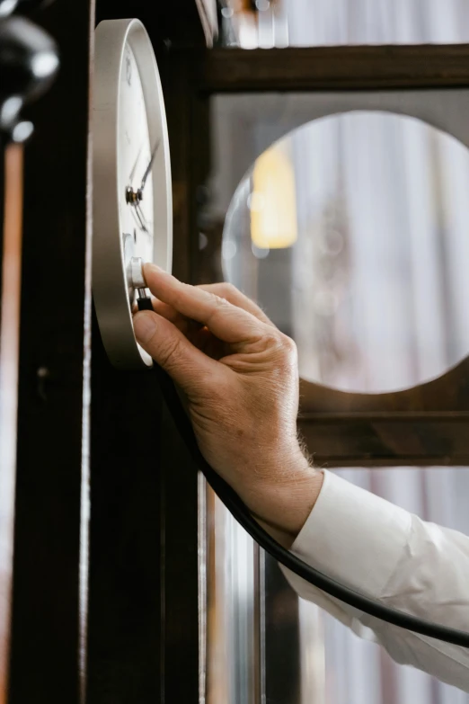 a close up of a person holding a clock, looking through a window frame, lab coat, opening door, plating