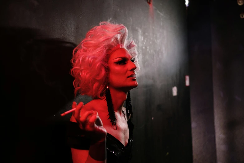 a woman with pink hair smoking a cigarette, inspired by Nan Goldin, pexels, transgressive art, drag queen, in a black room, premiere, carmen dell ’ orefice