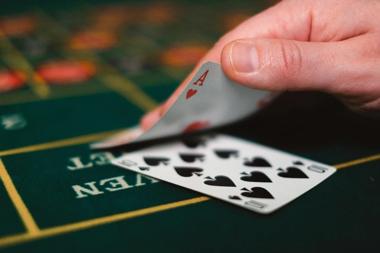 a close up of a person holding a playing card, pexels contest winner, gaming table, square, splash image, 1 0 / 1 0