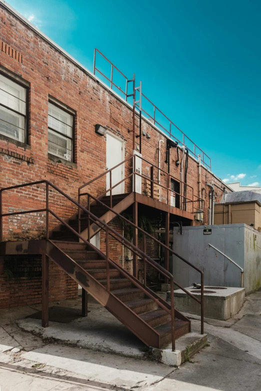 a red fire hydrant sitting in front of a brick building, long winding stairs going down, industrial space, brown, blue sky