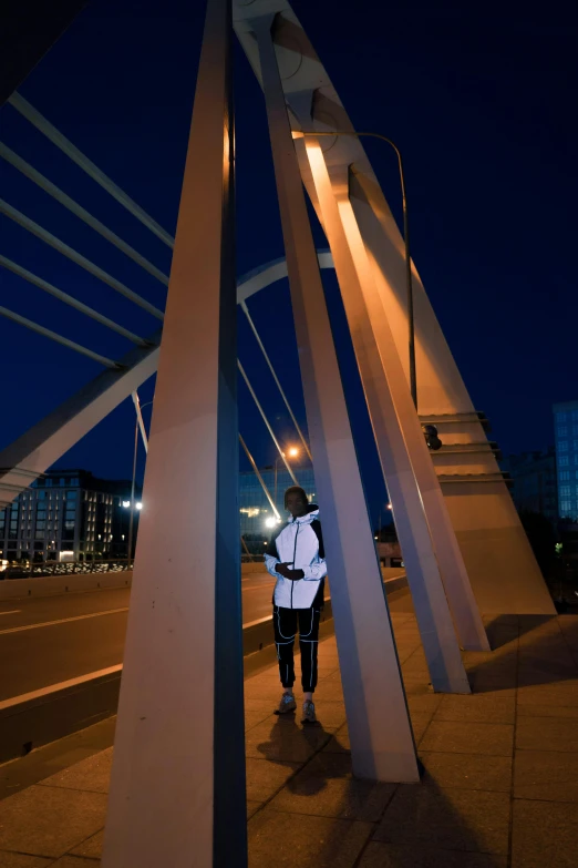 a person standing on a bridge at night, daniel libeskind, public art, hunched shoulders, photographed for reuters