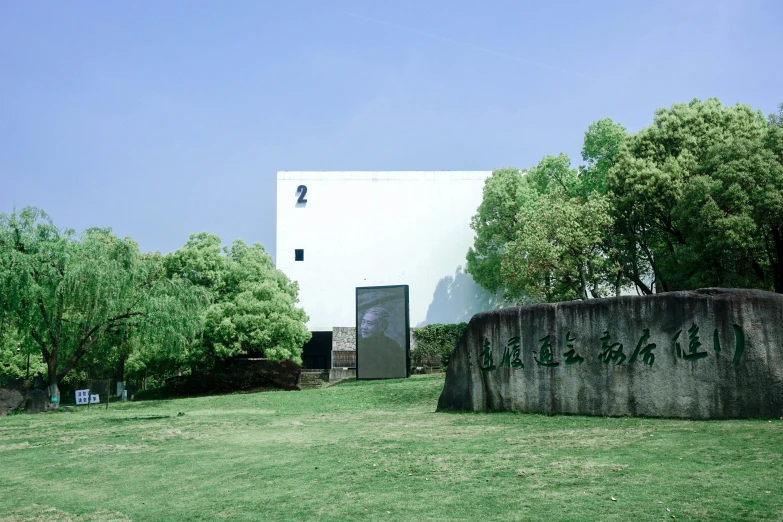 a white building sitting on top of a lush green field, inspired by Tadao Ando, shin hanga, feng zhu |, private academy entrance, 2022 photograph, tourist photo