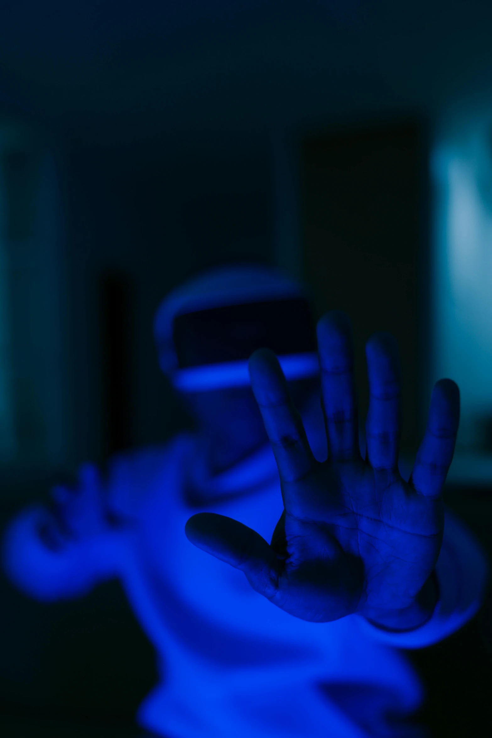 a man wearing a virtual reality headset in a dark room, a hologram, by Adam Marczyński, pexels, hands up, ((blue)), a portrait of an android, taken with sony alpha 9