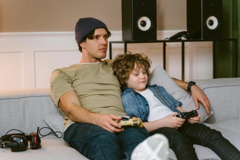 a man and a boy sitting on a couch playing video games, by Adam Marczyński, pexels, realism, husband wife and son, casually dressed, resting, advert