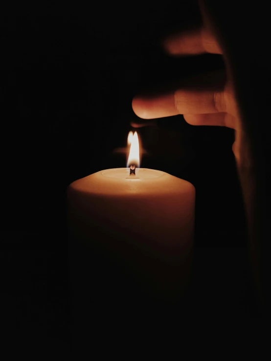 a hand holding a lit candle in the dark, profile image