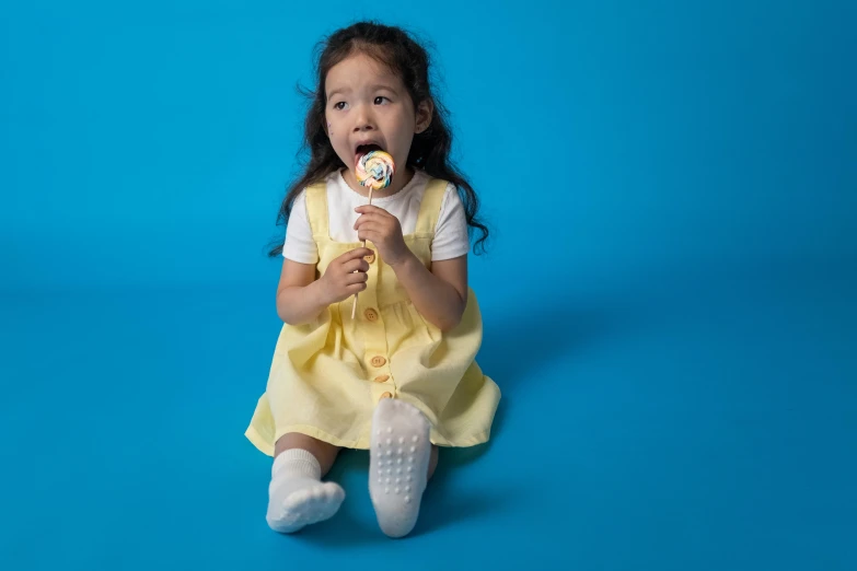 a little girl in a yellow dress eating a donut, inspired by Judith Leyster, pexels contest winner, pale blue outfit, lollipops, 9 0 mm studio photograph tiny, chinese