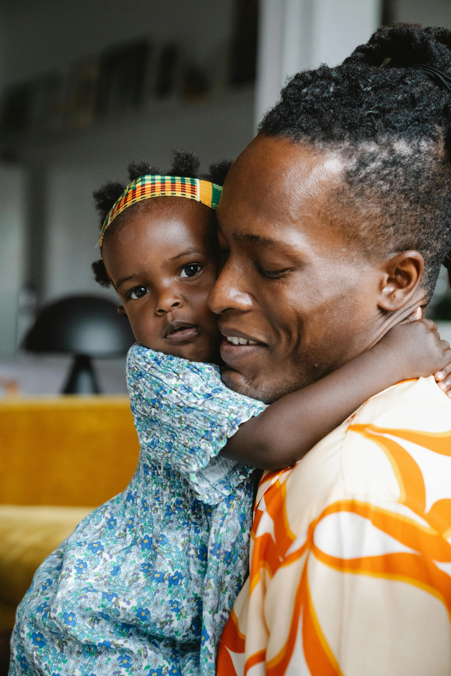 a woman holding a child in her arms, pexels contest winner, afrofuturism, daddy/fatherly, at home, lgbtq, slide show