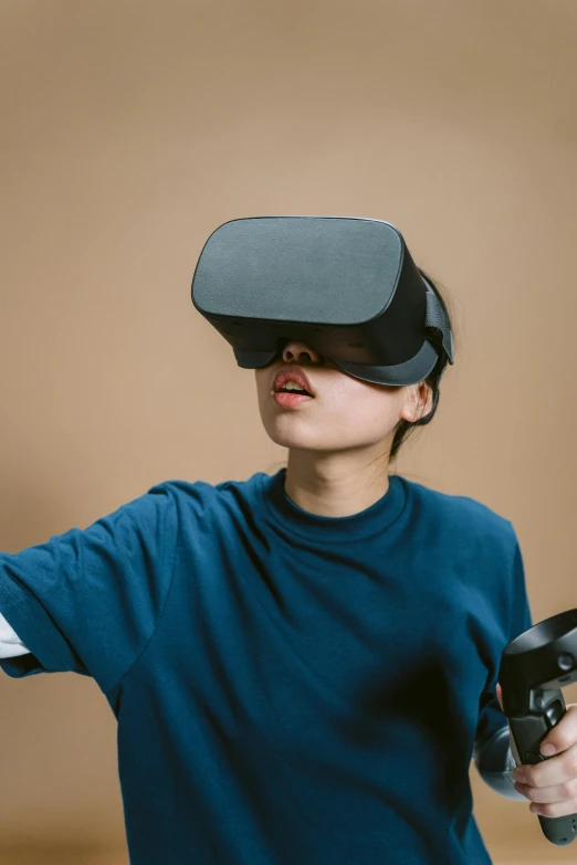 a boy in a blue shirt holding a video game controller, trending on unsplash, hypermodernism, big googles over her head, a young asian woman, oculus rift, square