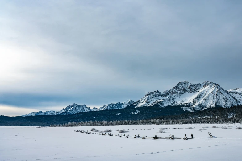 a person riding skis across a snow covered field, pexels contest winner, land art, craggy mountains, in a row, gray, fine art print