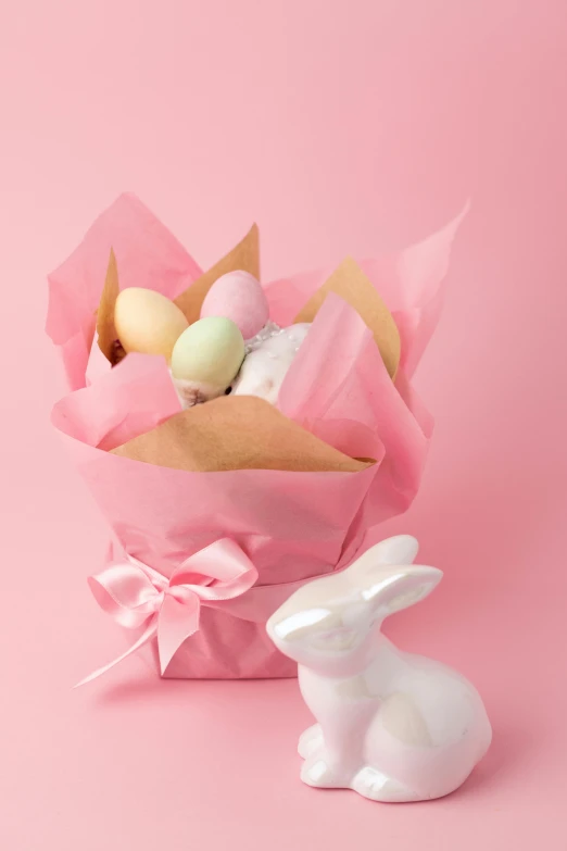 an easter basket with eggs and a bunny figurine on a pink background, by Lucette Barker, wrapped, tastes, full product shot, lush