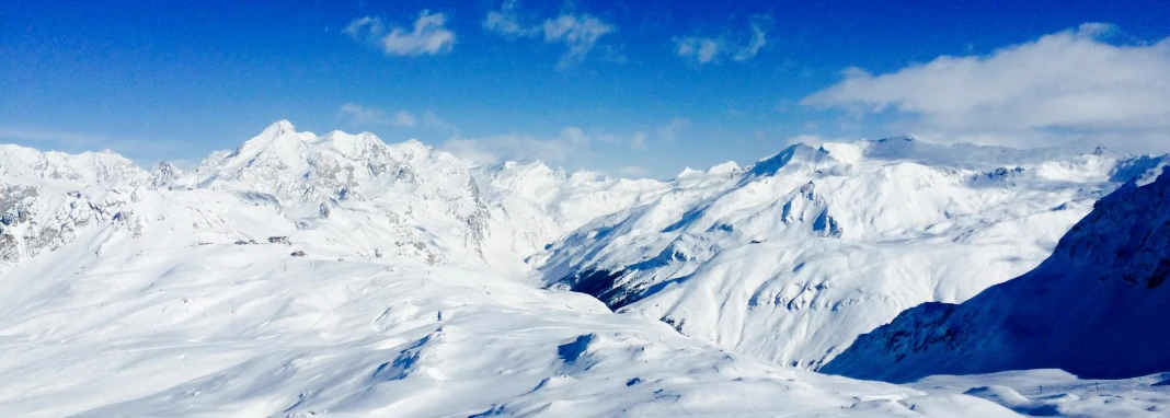 a man riding skis on top of a snow covered slope, by Werner Andermatt, pexels contest winner, “ aerial view of a mountain, blue liquid and snow, a cozy, panorama