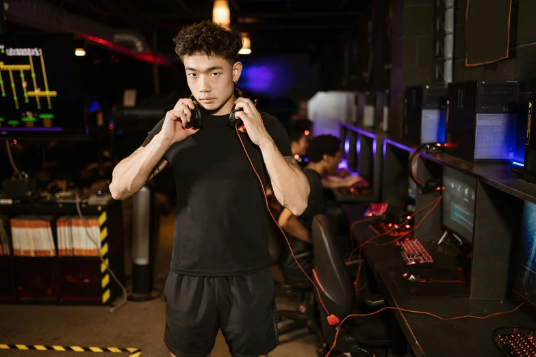 a man standing in front of a bunch of computers, a portrait, trending on pexels, realism, wearing gaming headset, black and red only, dim dingy gym, jinyiwei