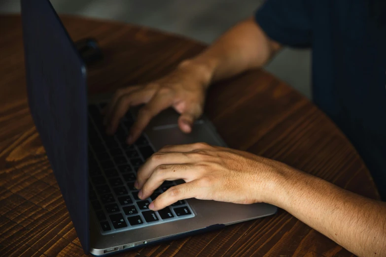 a close up of a person typing on a laptop, by Carey Morris, pexels, multiple stories, brown, background image, sitting at table