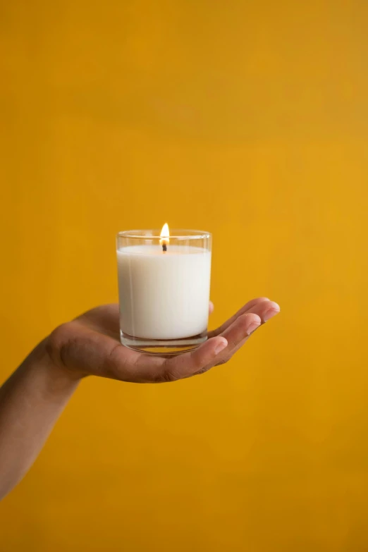 a person holding a candle in their hand, by Nina Hamnett, cream, small, displayed, hindu