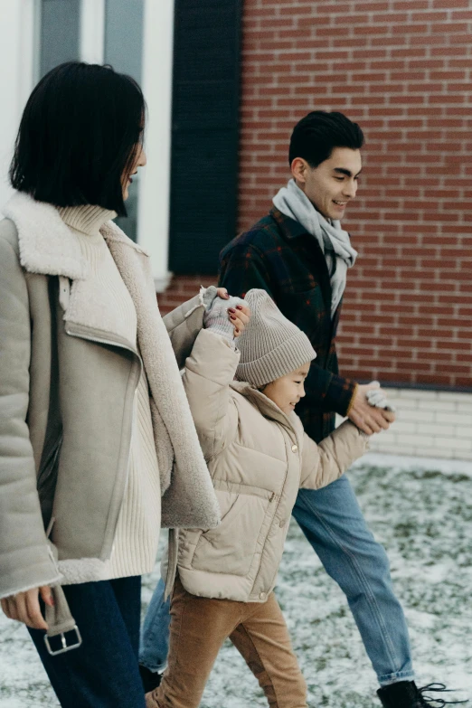 a couple of people that are walking in the snow, with a kid, walking through a suburb, light brown coat, profile image