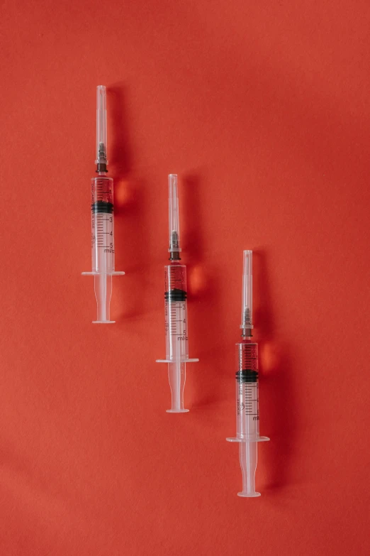 a group of sylls sitting on top of a red surface, syringes, detailed product shot, 3 - piece, hexagonal shaped