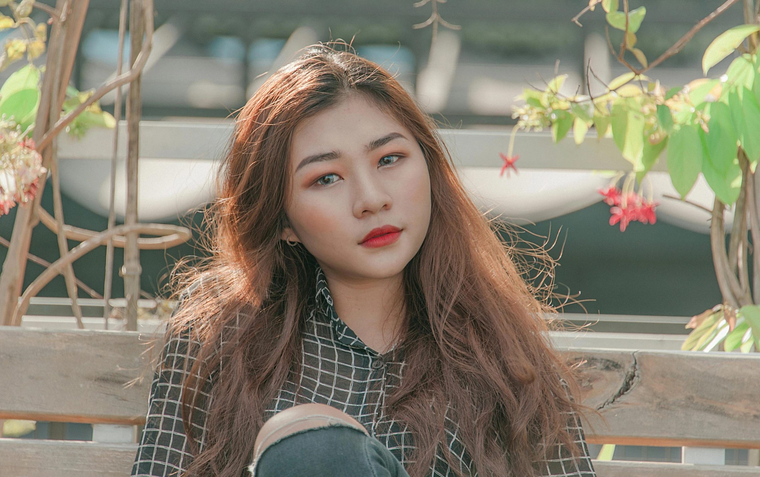 a woman sitting on top of a wooden bench, inspired by Kim Jeong-hui, trending on pexels, realism, brown red long hair, south east asian with round face, lipstick, 18 years old